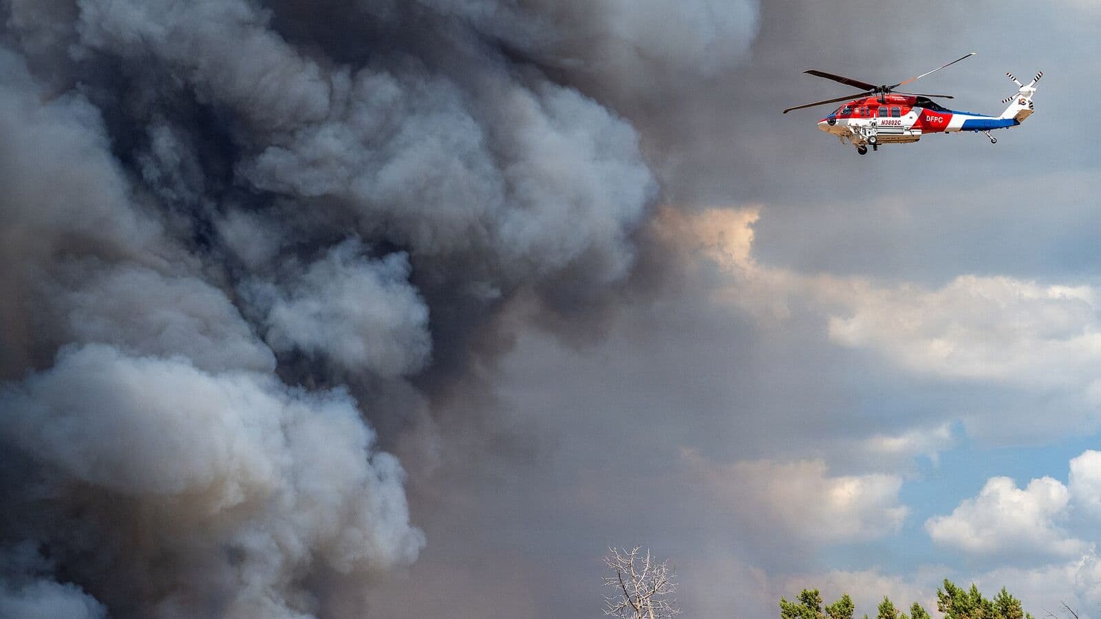 Firefighting helicopter flying near a smoke column from the Ferris Fire near Cortez, Colorado